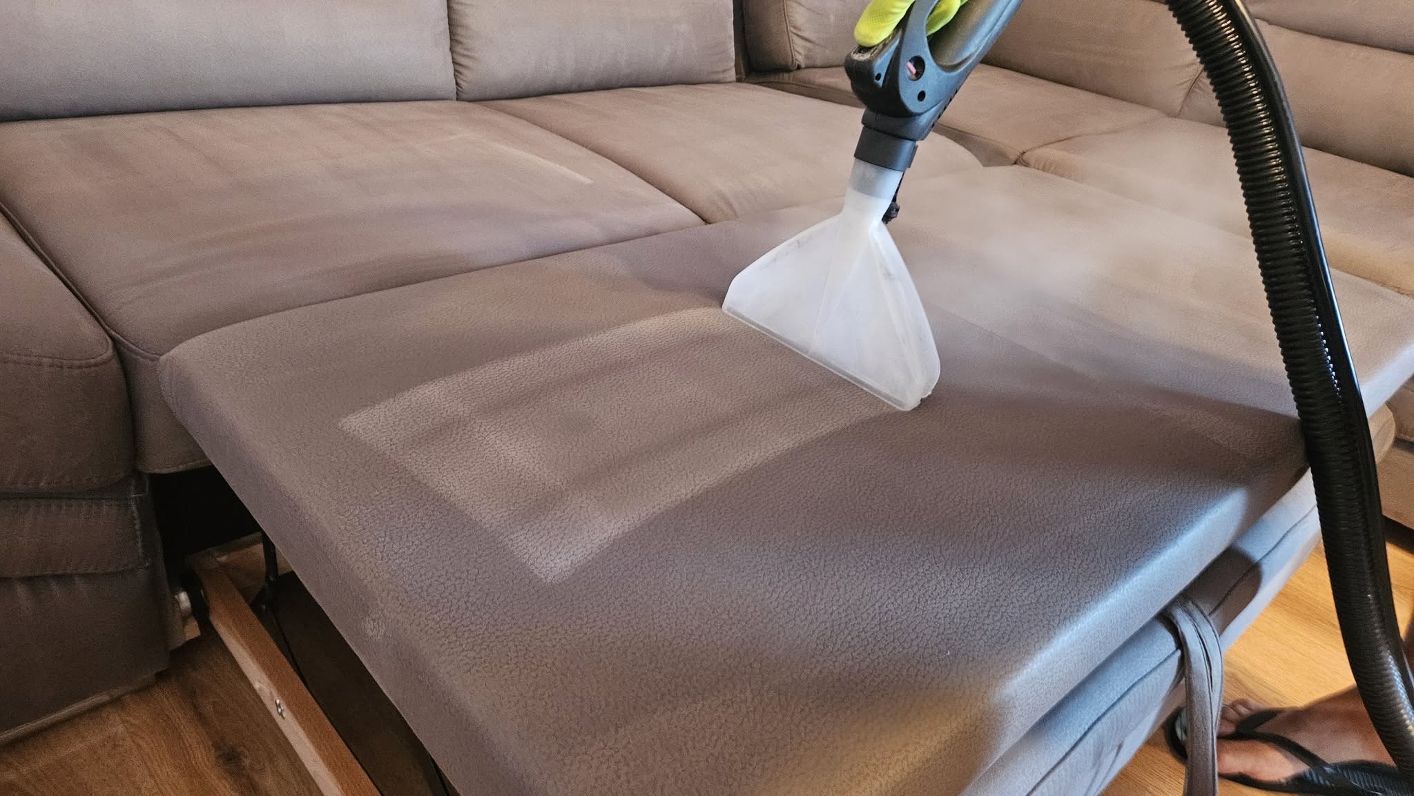 Curățarea cu echipament profesional de extracție a suprafeței textile a unei canapele extensibile în Oradea.
